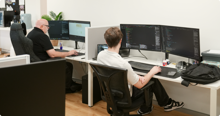 two click click media developers working at multi-monitor workstations in the norwest office, building ai-powered solutions.