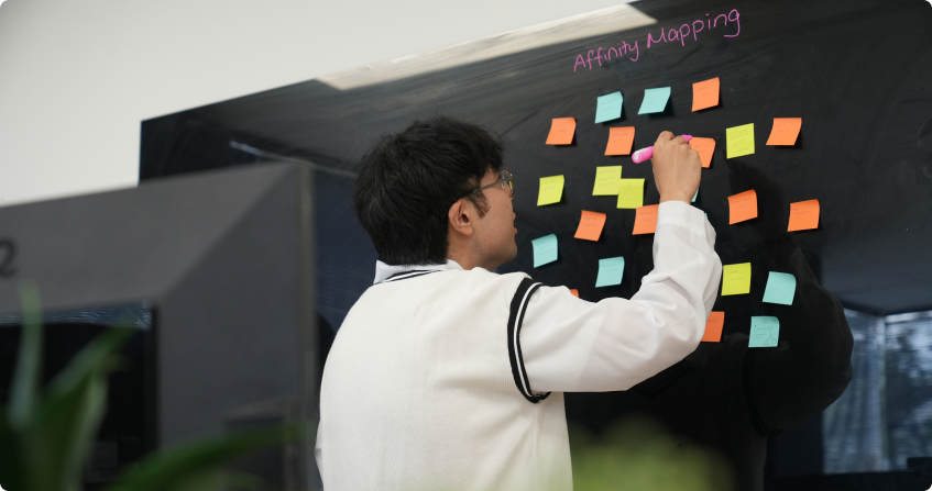 jerry placing sticky notes on a board labeled affinity mapping during a ux brainstorming session in the norwest office.